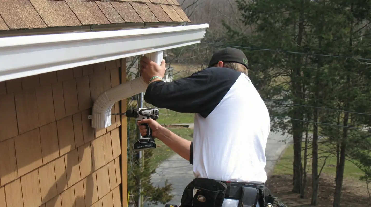 Professional contractor installing tan vinyl siding panels on a residential home exterior in Rochester, NY